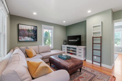 Contemporary living room featuring a light-toned sofa, green walls, and a television.
