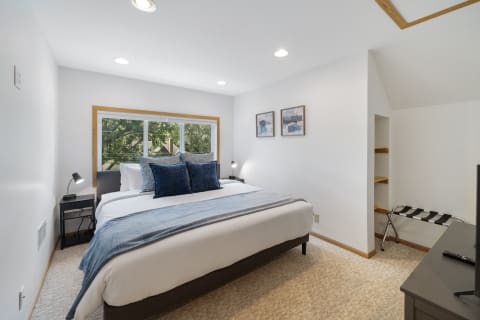 Modern bedroom with a large bed, blue pillows, and a scenic window view.