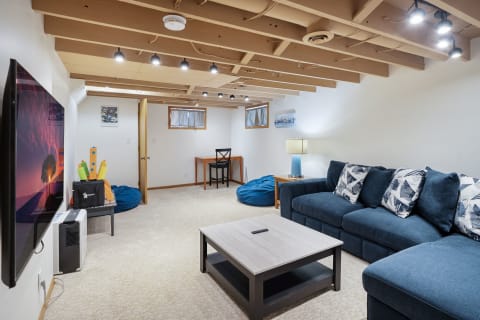 A comfortable basement lounge area featuring a blue couch, coffee table, and flat-screen TV.