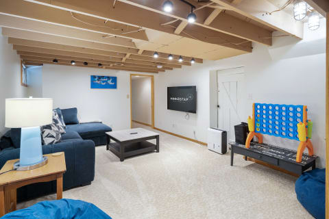 Cozy basement living room with a sectional sofa, coffee table, and game table.