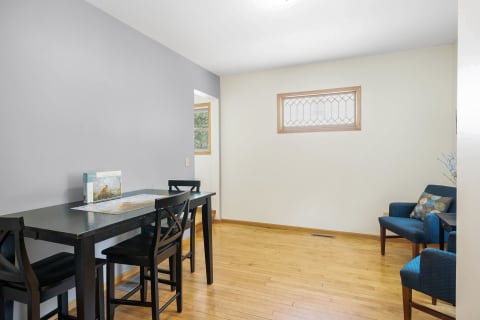 A dining area with a black table, blue chairs, and hardwood flooring.