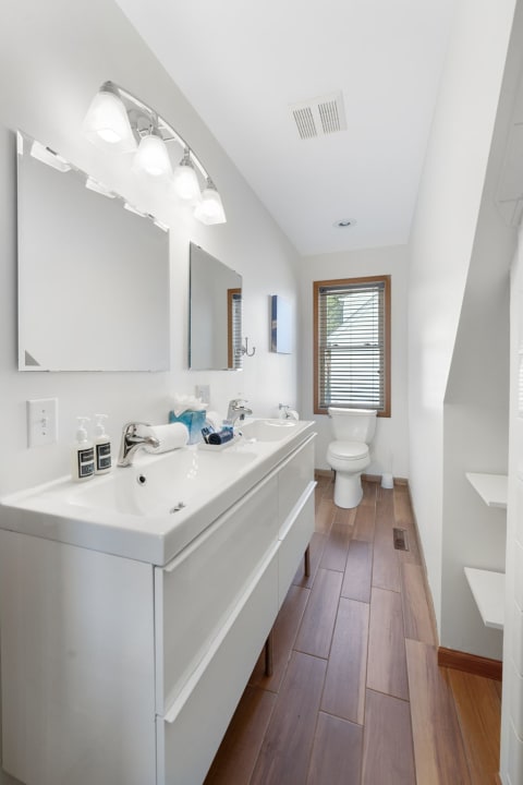 Contemporary bathroom with double sink vanity and wooden flooring.
