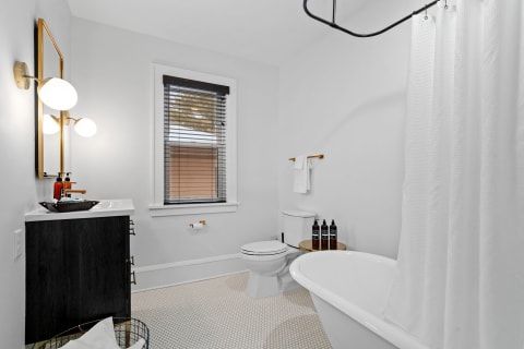 A contemporary bathroom with a freestanding bathtub, modern vanity, and warm lighting.