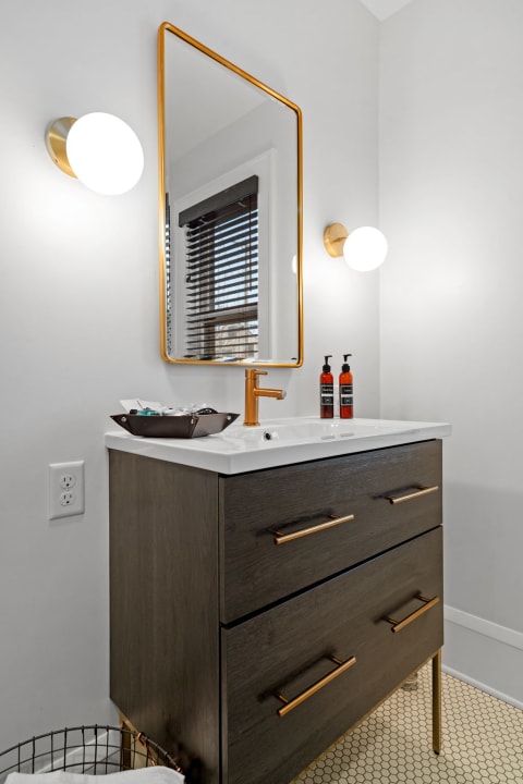 Modern bathroom vanity with gold accents and a mirror.
