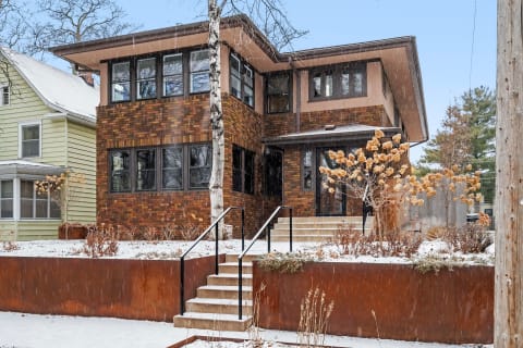 A modern brick house in winter with snow and dried plants.