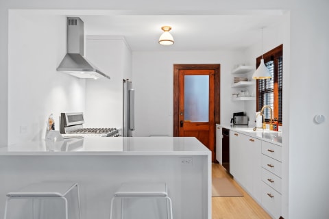 A modern kitchen with white cabinetry, stainless steel appliances, and warm wooden details.