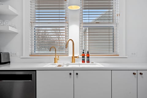 A modern kitchen sink with a golden faucet and clean design under natural light.
