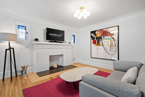 Modern living room with grey sofa, marble coffee table, abstract art, and fireplace.