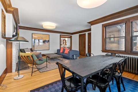An inviting living room with a green armchair, blue sofa, dining table, and wooden accents.