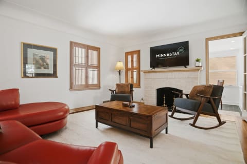 Cozy living room with red leather seating, wooden coffee table, and stone fireplace.