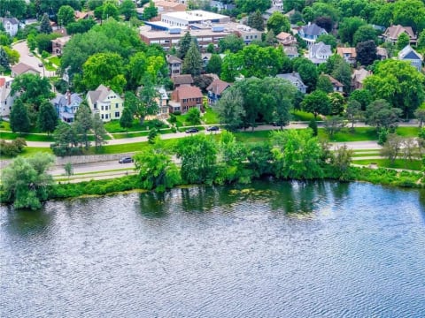 Aerial view of a charming lakefront neighborhood with various architectural styles and green surroundings.