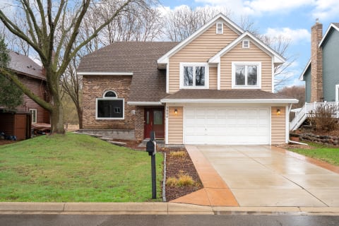 A two-story house with brick and siding exterior and a spacious driveway.