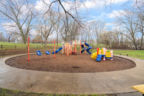 Playground with colorful equipment including swings and slides located in a park.