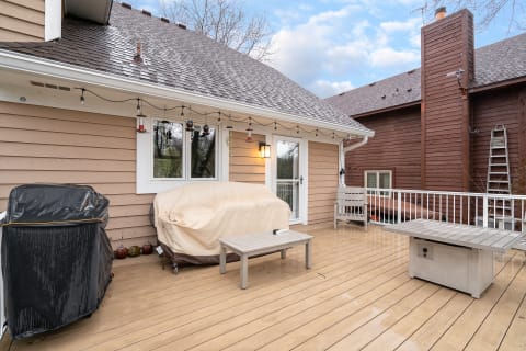 Outdoor patio with wooden deck, grill cover, and decorative lanterns.