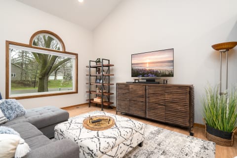 Cozy living room with gray sectional sofa, wooden furniture, and a large window.