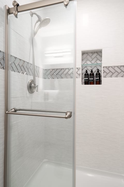 A sleek modern shower with a glass door and decorative herringbone tile.