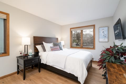 A well-decorated bedroom featuring a bed, nightstand, and window with natural light.