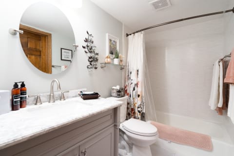 Modern bathroom featuring gray cabinet, white marble countertop, and decorative elements.