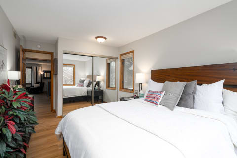 Cozy bedroom with a bed, decorative pillows, and a mirrored closet reflecting the room's ambiance.