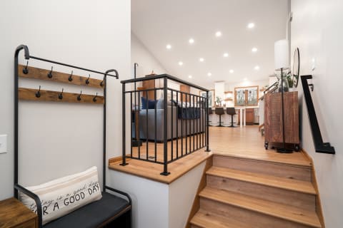 Entryway with coat rack and stairs leading to living area.