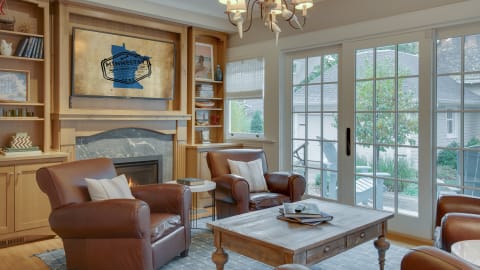 Relax in this elegant living room with leather armchairs, warming fireplace, and French doors opening to your private outdoor space.