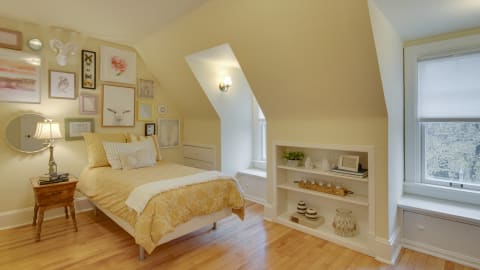 Attic bedroom with a yellow color scheme, featuring a bed, nightstand, and decor on the walls.