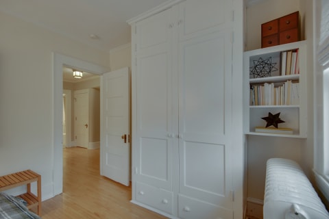 Cozy bedroom with built-in storage and shelves filled with books and decor.
