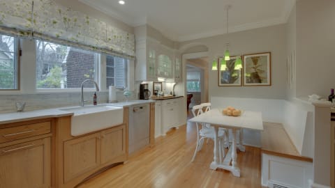 Bright kitchen featuring a farmhouse sink, floral curtains, and a cozy breakfast nook.