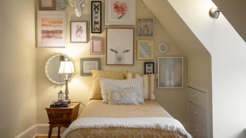 A charming attic bedroom with decorative artwork and cozy lighting.