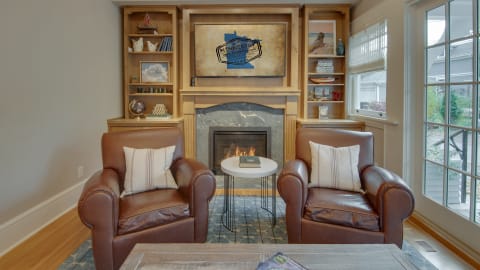 Cozy living room with leather chairs, fireplace, and decorative shelves.