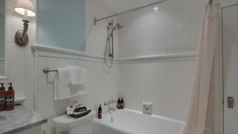 A spacious bathroom featuring a tub-shower combo with elegant tiles and a marble countertop.