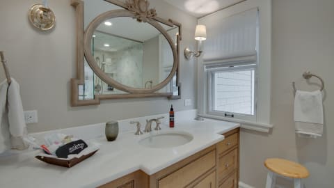 A stylish bathroom with a large round mirror, marble countertop, and elegant fixtures.