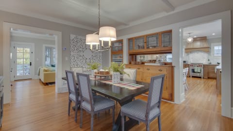 A beautifully designed dining room with a dark wooden table and striped chairs, complemented by soft lighting and decorative elements.