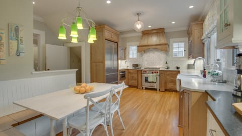 A modern kitchen with wood accents, professional appliances, and a breakfast table with fresh oranges.