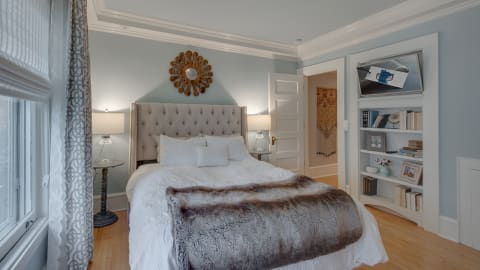 A serene bedroom with a tufted bed, decorative pillows, warm lighting, and stylish decor.
