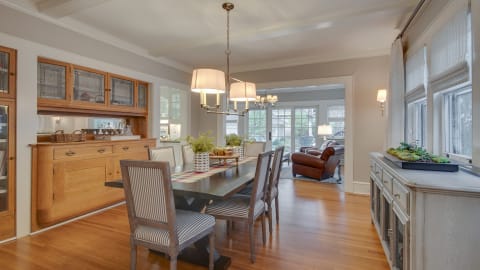 Elegant dining room with a spacious table, striped chairs, chandelier, and oak buffet.