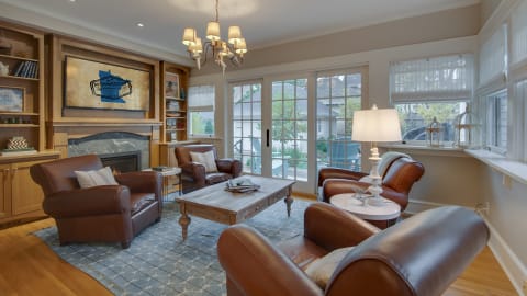 A warm and inviting living room with leather chairs, a fireplace, and ample natural light.