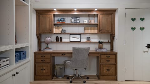 A cozy workspace with wood cabinetry, a chair, and decorative items on the shelves.