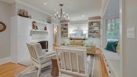 Cozy living room with nautical decor, featuring a yellow sofa, decorative shelves, and a sunny window nook.