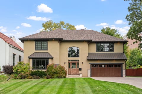 A contemporary two-story house with a beige exterior and landscaped front yard.