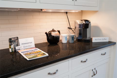 Kitchen countertop with coffee maker, mugs, teapot, and local pamphlets.