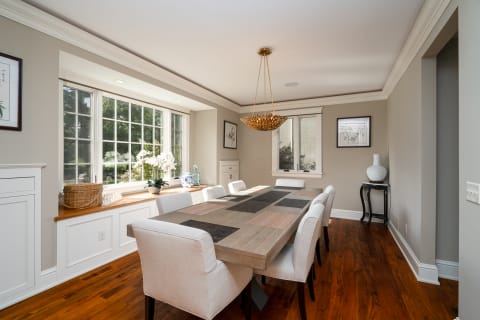 A stylish dining room featuring a dining table, elegant chandelier, and large windows.