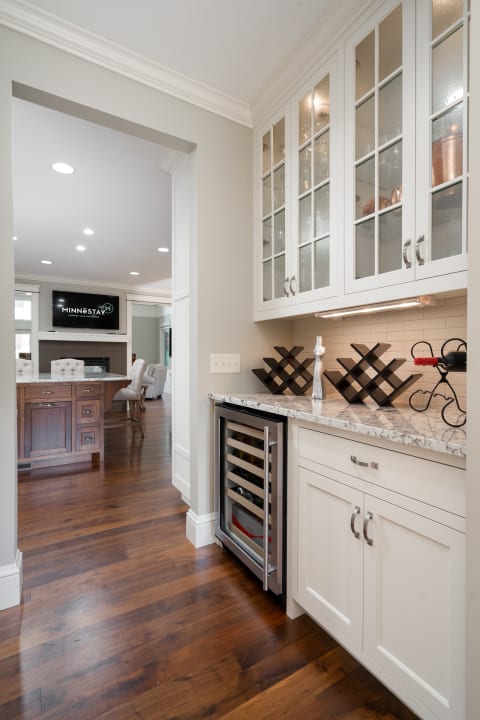 Stylish kitchen corner featuring a wine cooler and glass-paned cabinets.