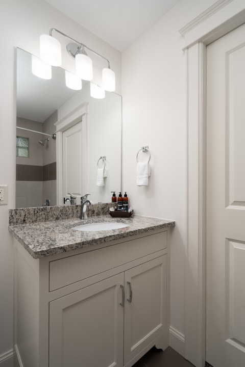 A modern bathroom featuring a granite countertop, stylish lighting, and neatly arranged toiletries.