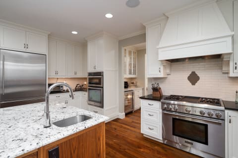 Spacious modern kitchen with granite island, stainless steel appliances, and white cabinetry.