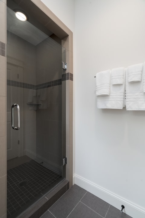 Modern shower enclosure with glass door and white towels hanging on a rack.