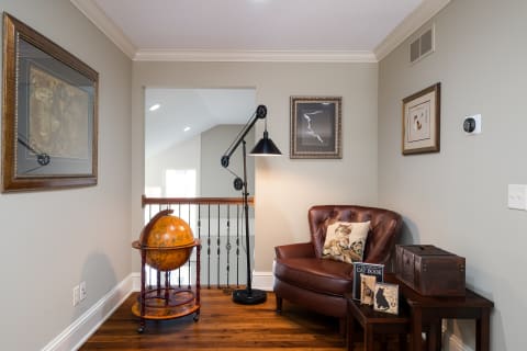 A corner of a home featuring a globe, leather armchair, and decorative artworks.