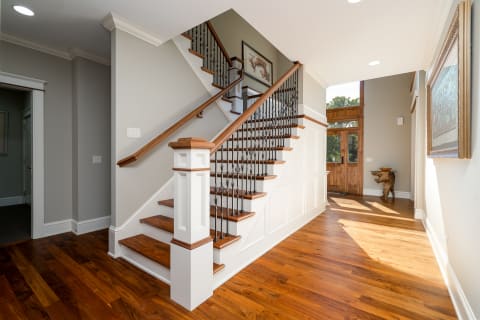 Foyer featuring a staircase with wooden steps and wrought iron railings, brightened by natural light.
