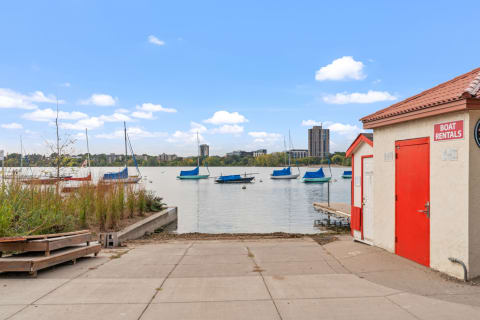 Lakeside boat rental area with sailboats in the water and a rental shack.