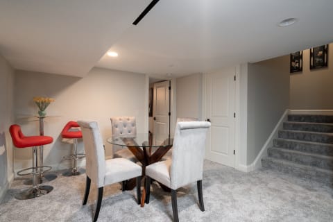 Stylish basement dining area featuring a glass table and cozy seating.